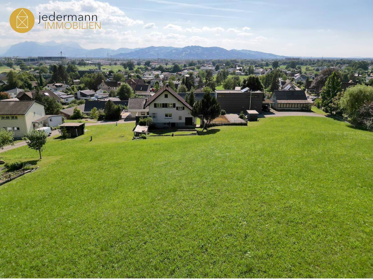 Luftaufnahme des Hauses inmitten einer weiten grünen Landschaft mit Bergblick.