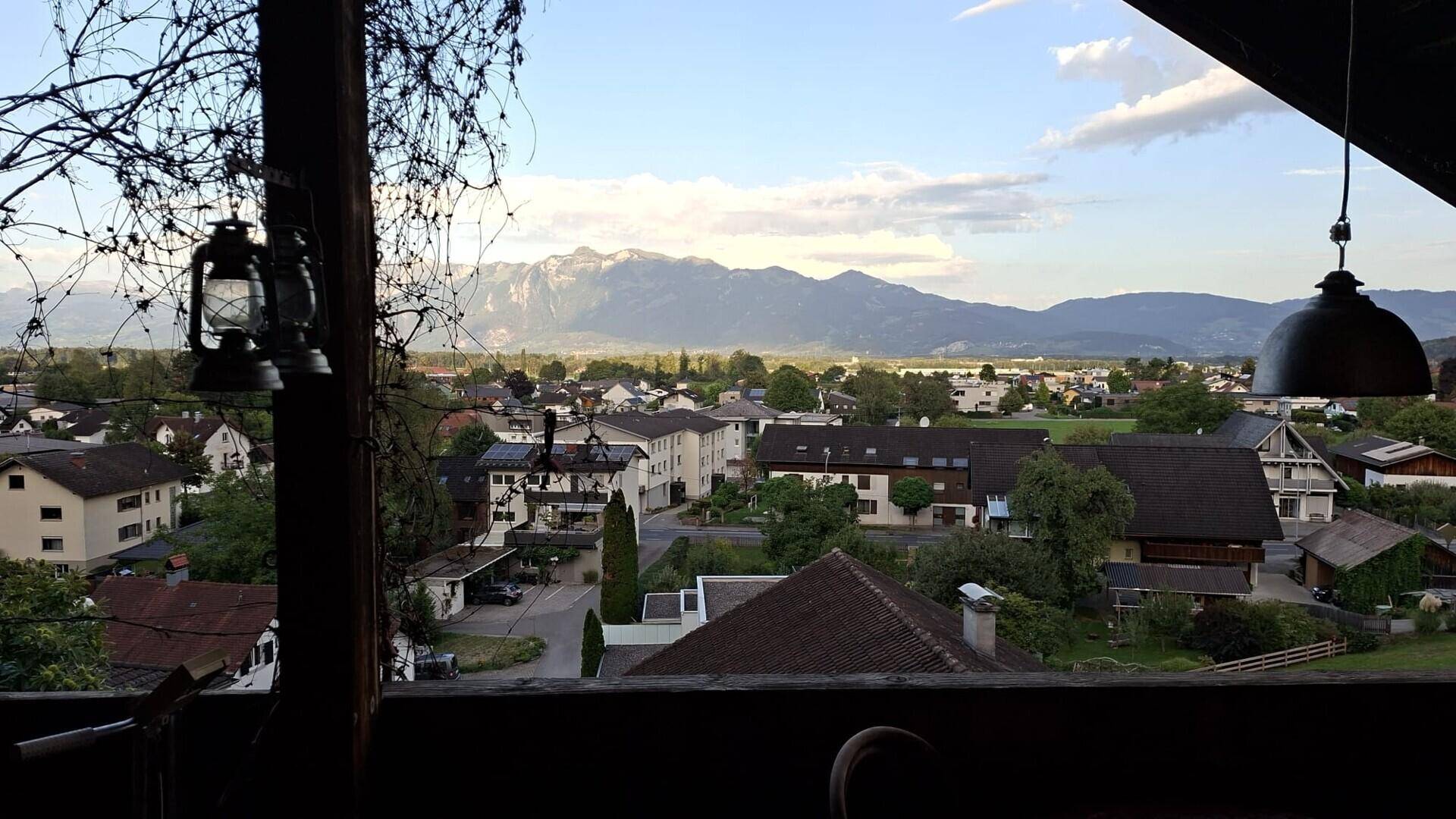 Malerischer Ausblick vom Balkon auf die umliegende Berglandschaft und die darunterliegende Ortschaft.