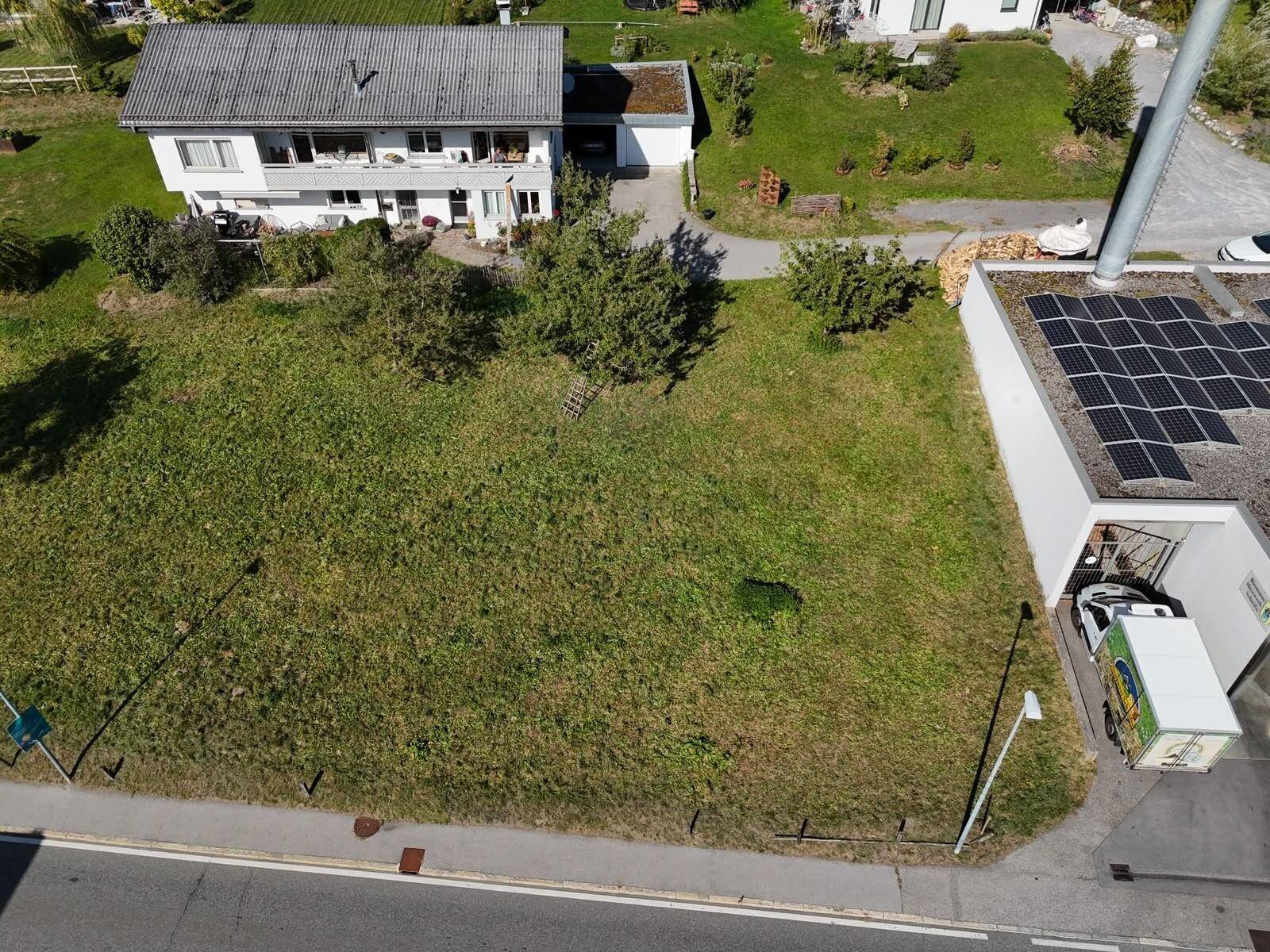 Luftaufnahme eines Grundstücks neben einem Gebäude mit Solaranlage und einem Wohnhaus.