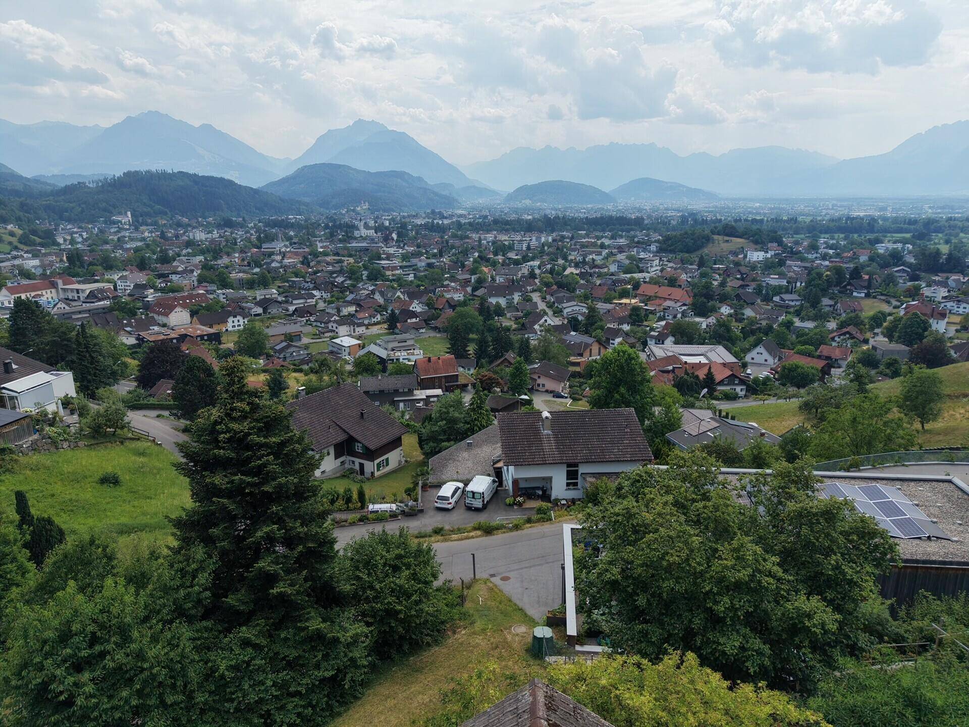 Weitläufige Luftaufnahme einer Stadt oder eines Dorfes mit vielen Häusern und Bergen im Hintergrund.