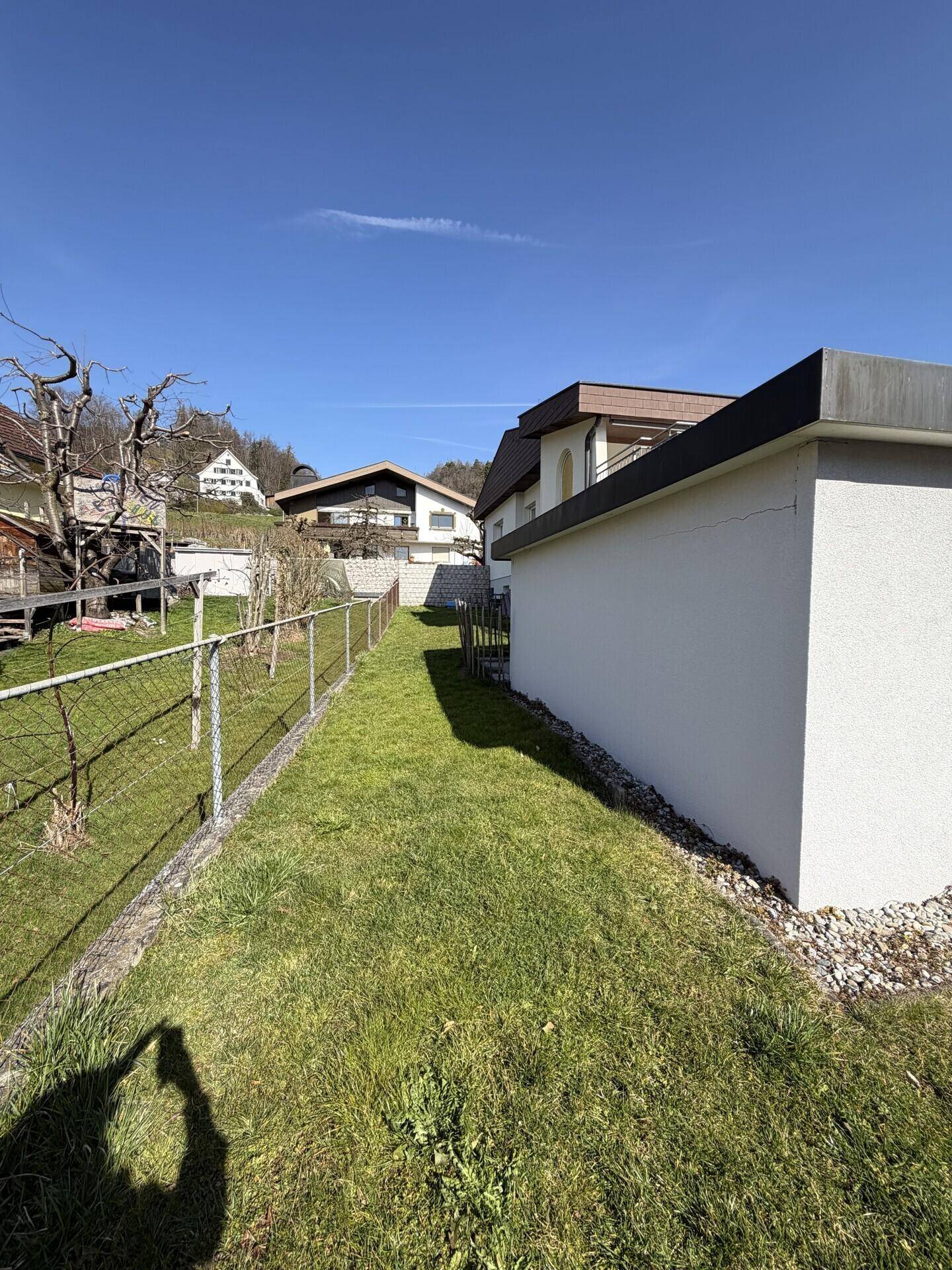 Seitlicher Gartenbereich mit Rasenfläche und Blick auf die umliegende Bebauung.