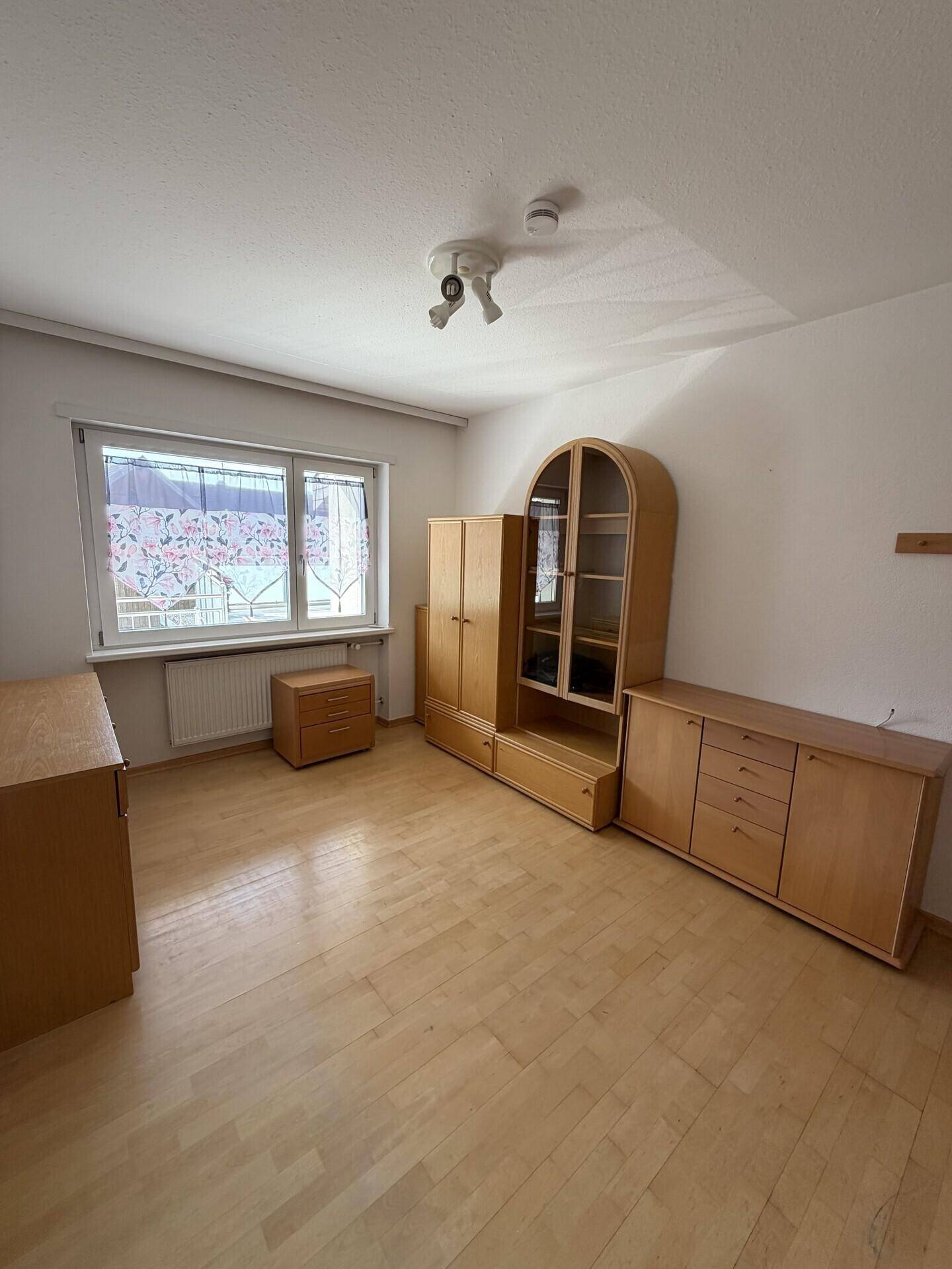 Heller Raum mit Parkettboden und Holzmöbeln, ideal als Schlaf- oder Arbeitszimmer.