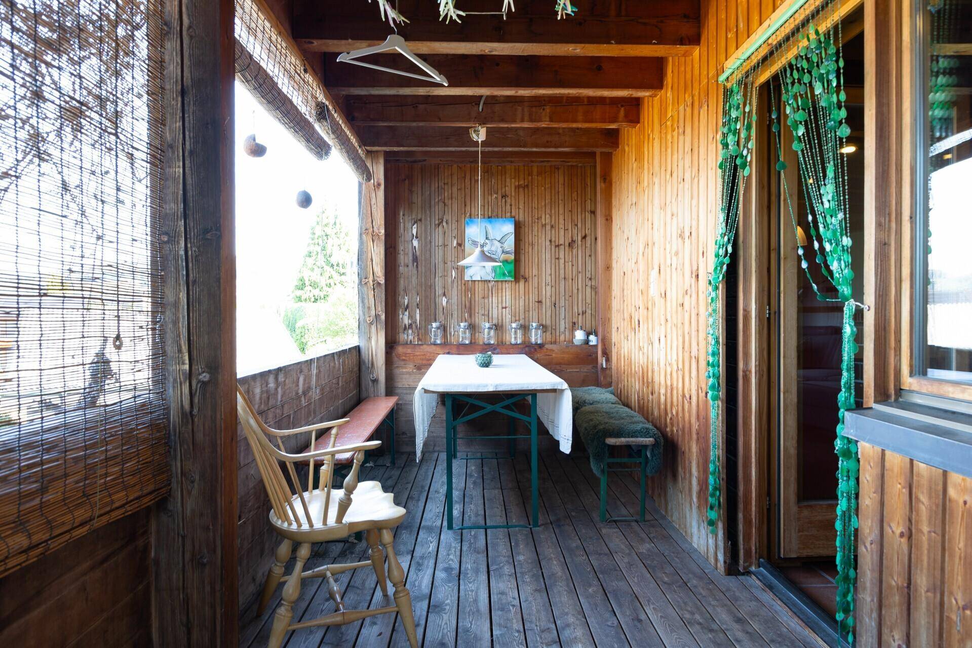 Überdachter Balkon mit Holzverkleidung und Sitzgelegenheiten, ideal für entspannte Stunden im Freien.