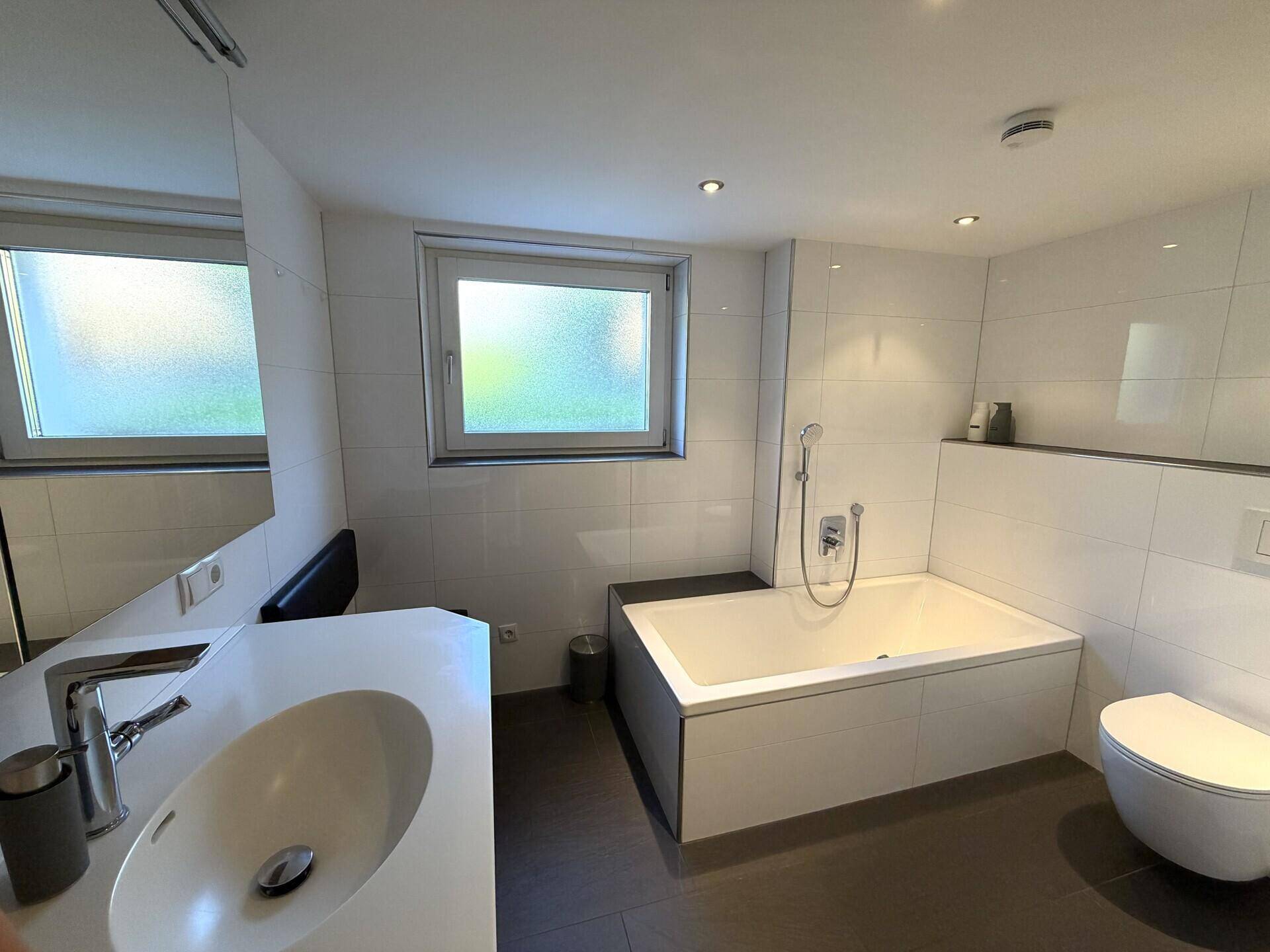 Modernes Badezimmer mit Badewanne, Einzelwaschbecken und Fenster.