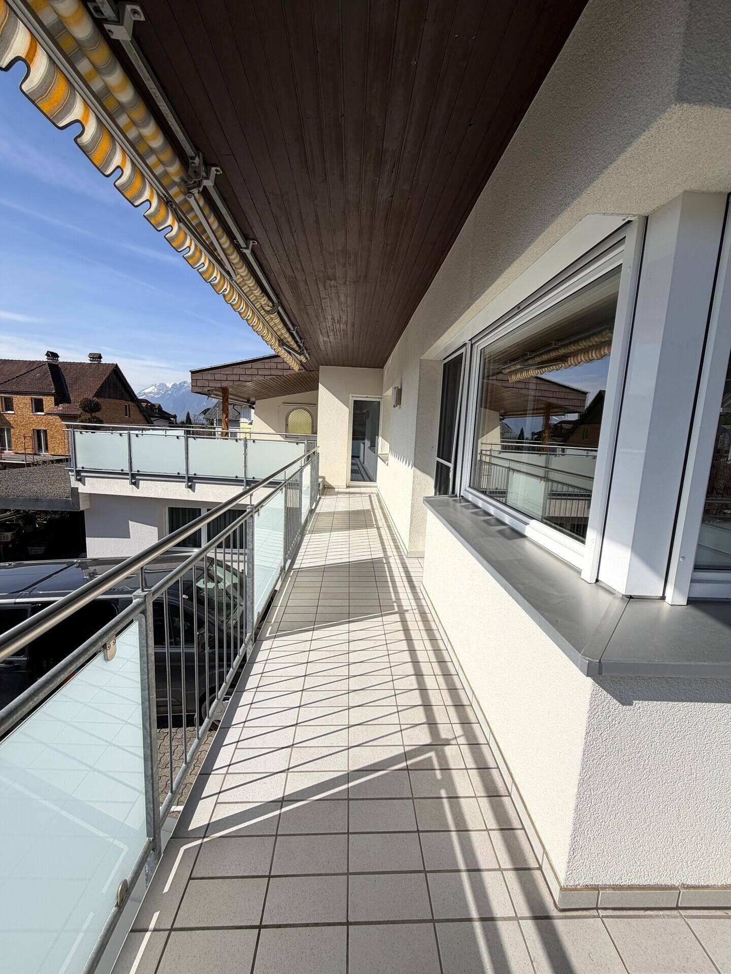 Geräumiger Balkon mit Fliesenboden, Markise und Zugang zu den Innenräumen.