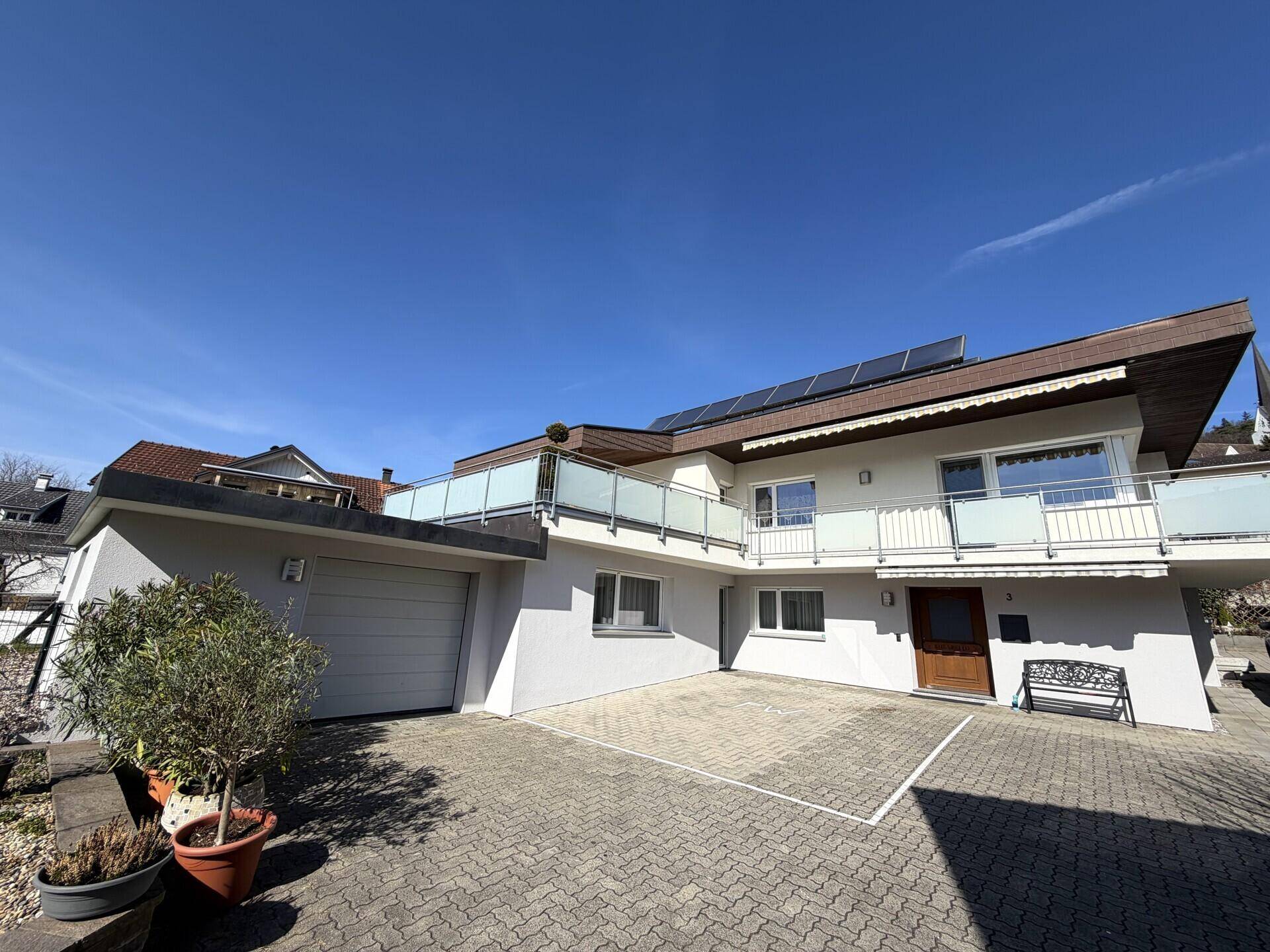 Ansicht des modernen Hauses mit Solaranlage auf dem Dach und großzügigen Balkonen.