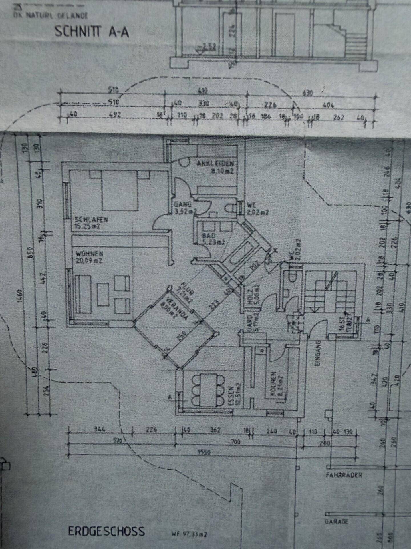 Grundriss des Erdgeschosses mit Wohnzimmer, Küche, Essbereich, Veranda und Schlafzimmer.