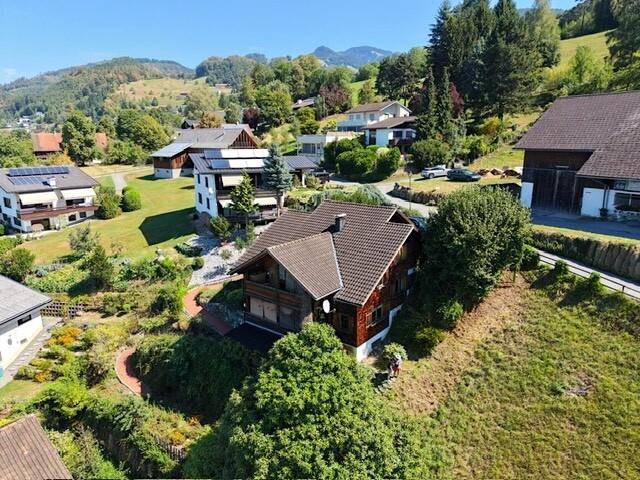 Weitläufige Luftaufnahme des Hauses eingebettet in eine grüne Hügellandschaft mit Fernblick.