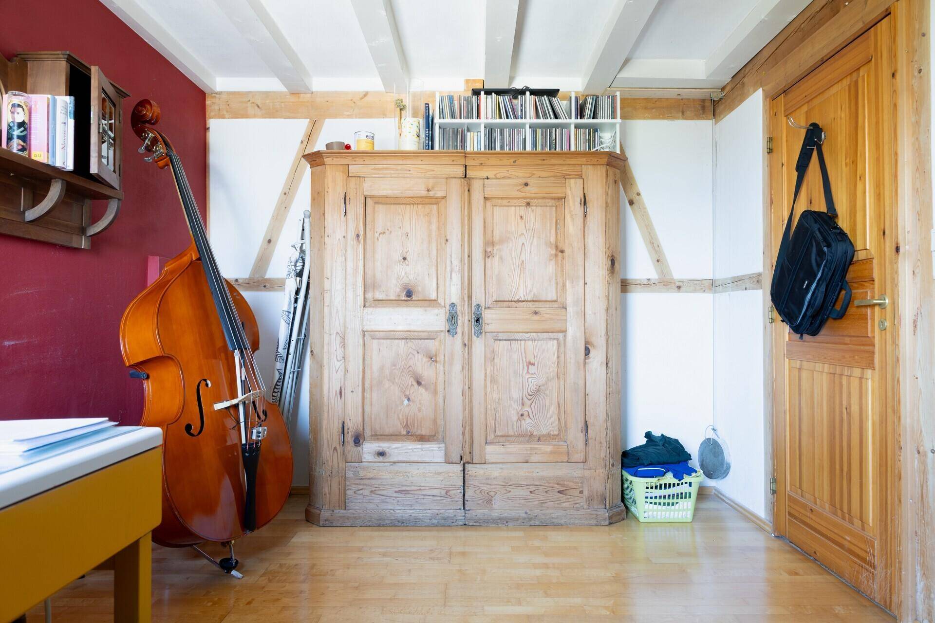 Arbeitszimmer mit großem Holzschrank, Holzbalken und roter Wand, bietet viel Stauraum.