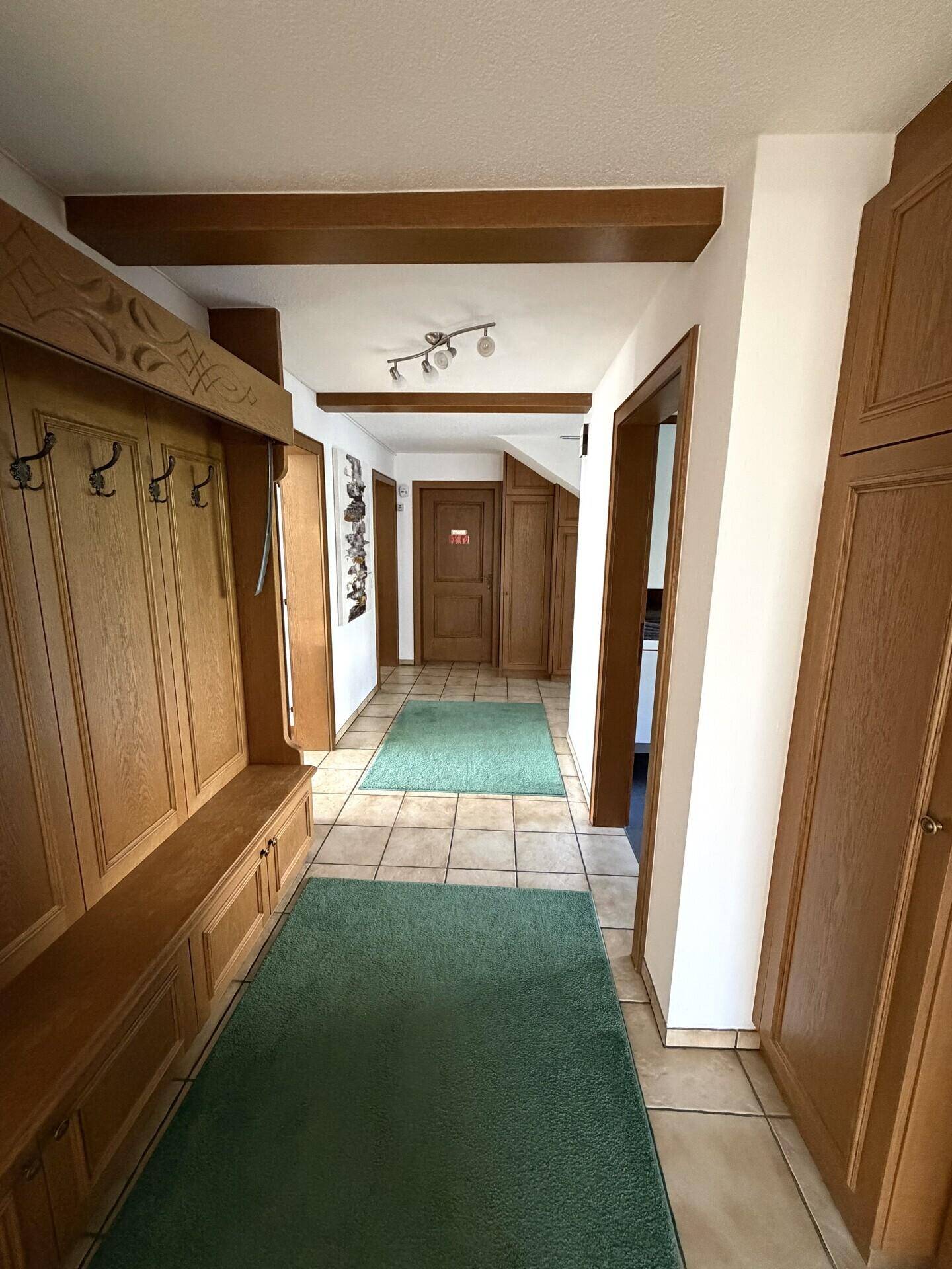 Geräumiger Flur mit Holzvertäfelung, Garderobe und Fliesenboden.