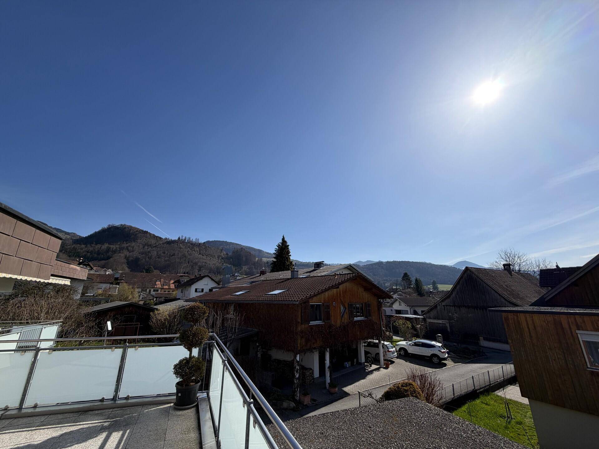 Weitläufiger Blick vom Balkon auf die umliegende Wohngegend und grüne Hügel.