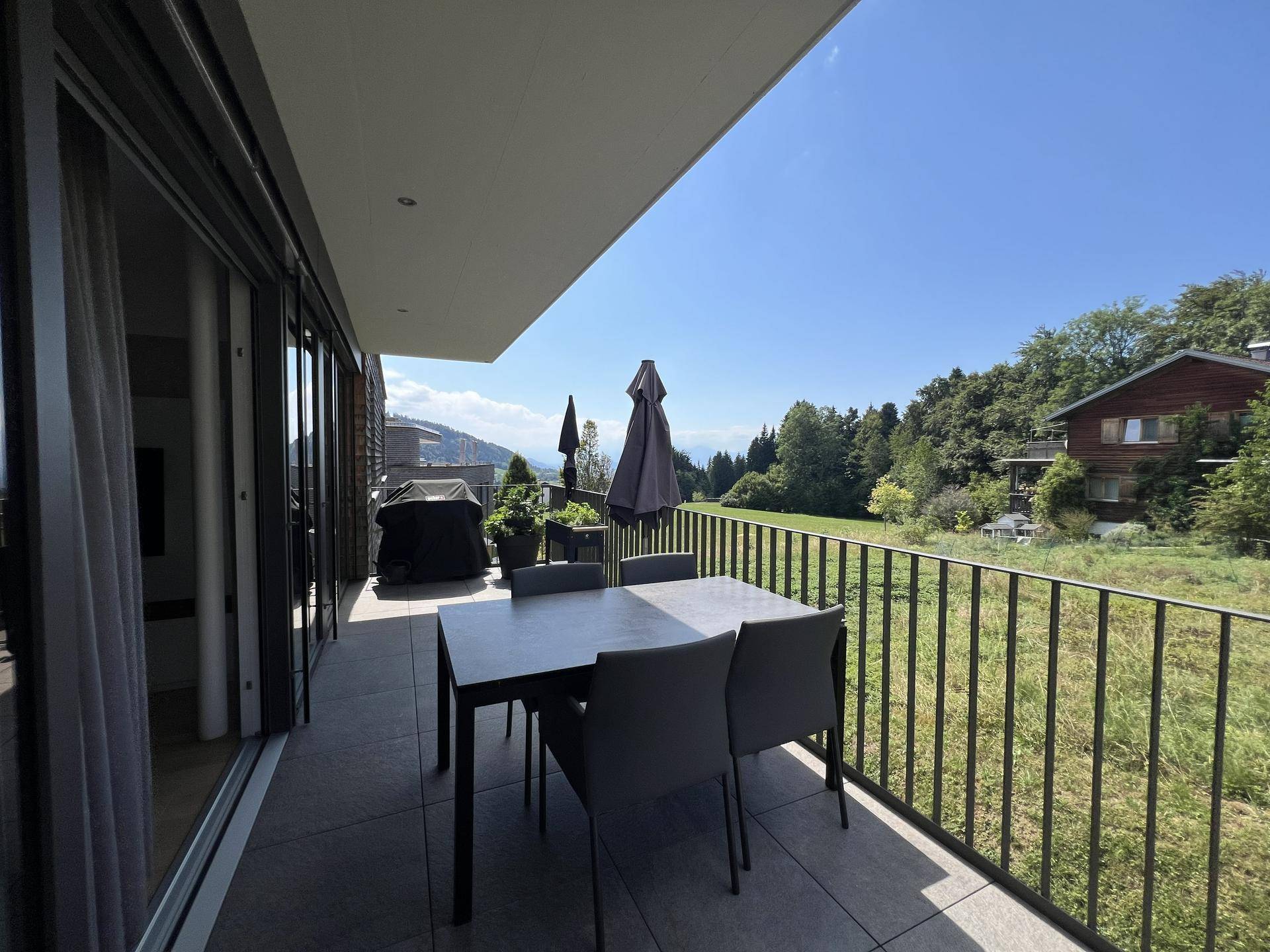 Heller Balkon mit Sitzgelegenheiten und Panoramablick auf die umliegende Natur und Berge.