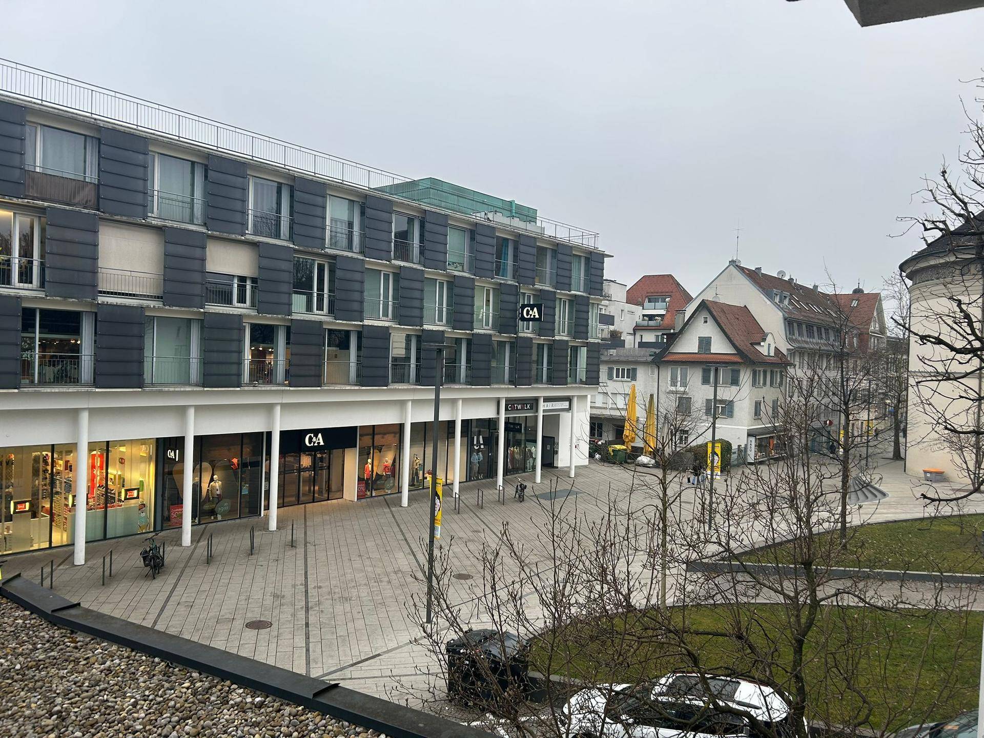 Blick auf eine belebte Einkaufsstraße mit modernen Gebäuden und Geschäften.