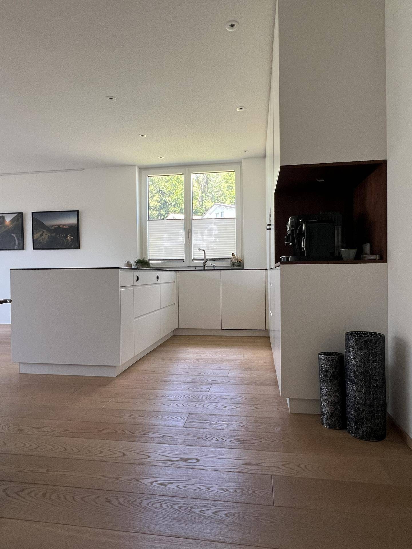 Geräumige, helle Küche mit Kochinsel, Spülbereich am Fenster und integrierter Kaffeemaschine.