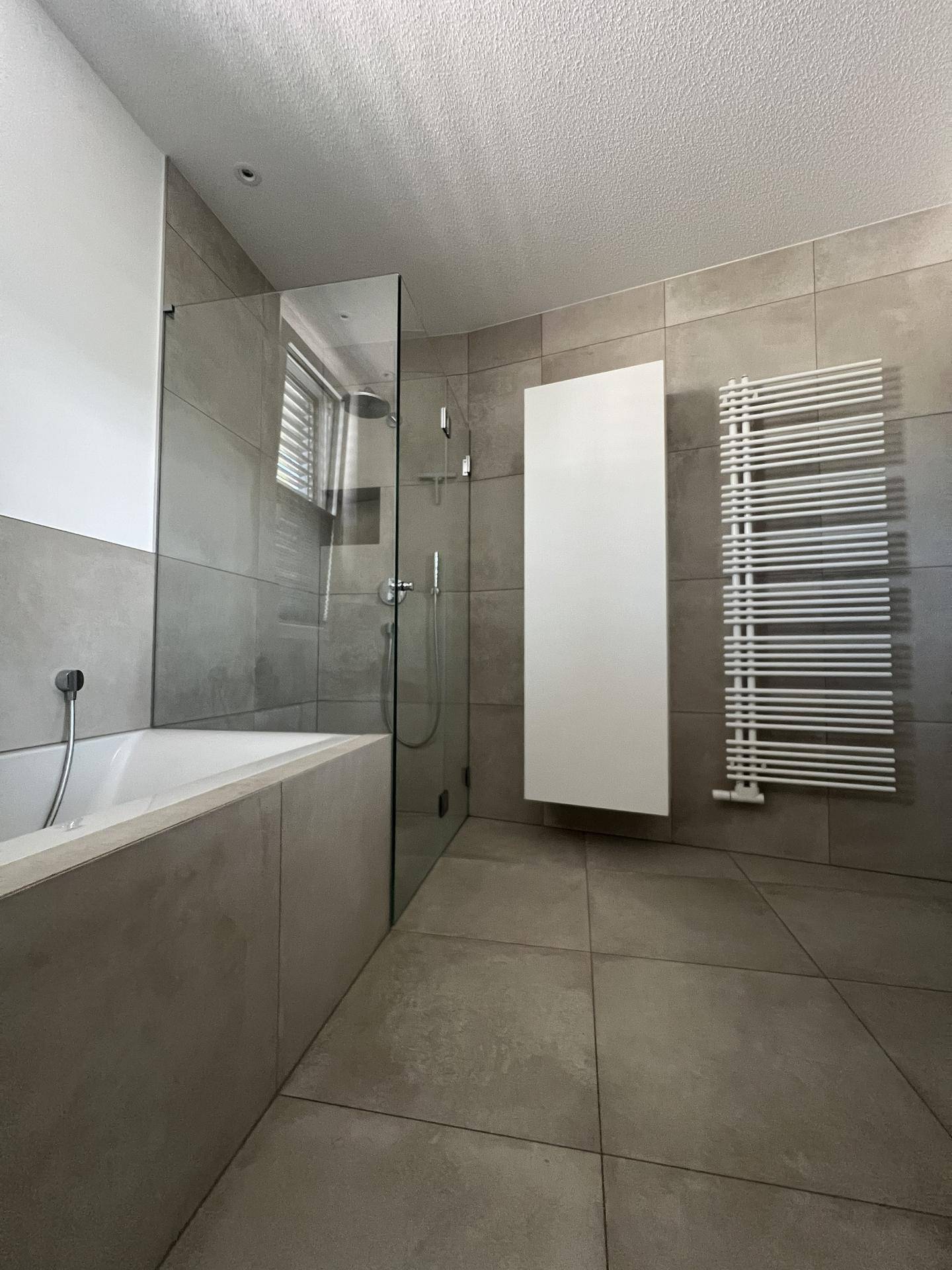 Elegantes Badezimmer mit begehbarer Dusche, Badewanne und beheiztem Handtuchhalter.