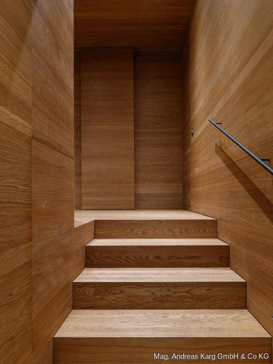 Holztreppe in einem eleganten Flur mit durchgehender Holzverkleidung und minimalistischem Geländer.