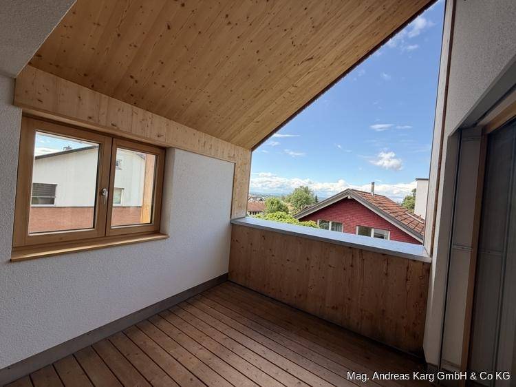 Gemütlicher, überdachter Balkon mit Holzboden und Holzverkleidung, ideal für entspannte Stunden mit Aussicht.