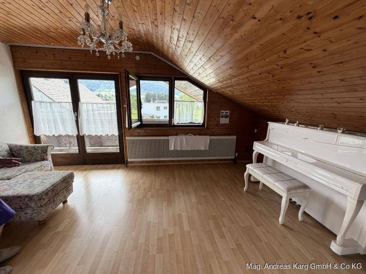 Gemütlicher Wohnbereich im Dachgeschoss mit Holzverkleidung, Schrägdach und Klavier.