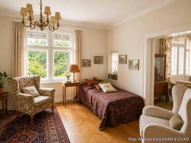Gemütliches Schlafzimmer mit Parkettboden, floralen Sesseln und Zugang zu einem weiteren Raum.