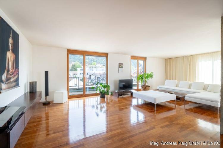 Helles Wohnzimmer mit glänzendem Parkettboden, weißen Möbeln und Zugang zum Balkon.