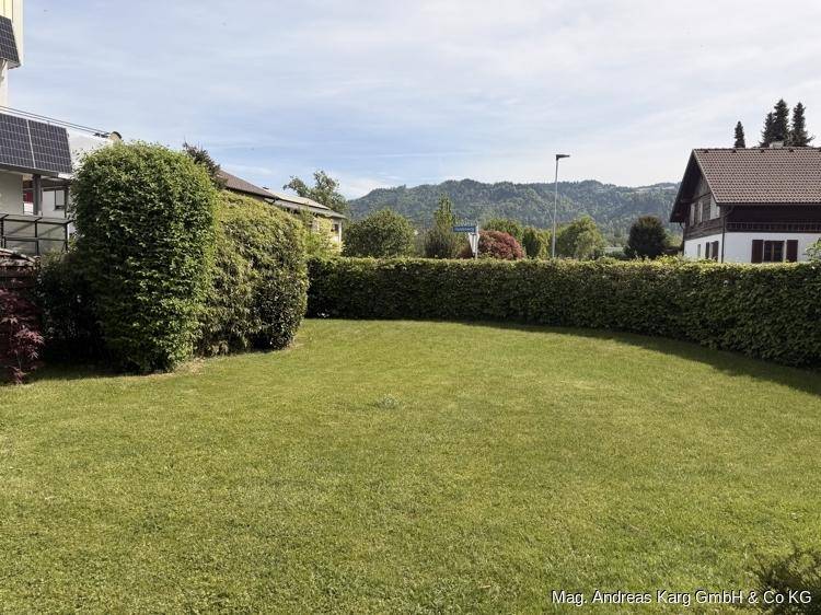 Großer, gepflegter Rasenbereich mit Hecke und Blick auf die umliegende Hügellandschaft.