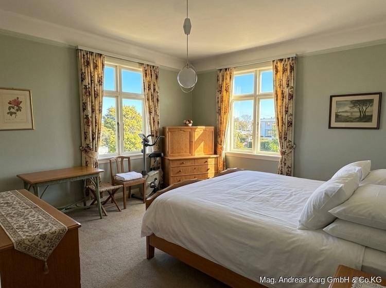 Geräumiges Schlafzimmer mit Doppelbett, Fitnessgerät und hellgrünen Wänden.