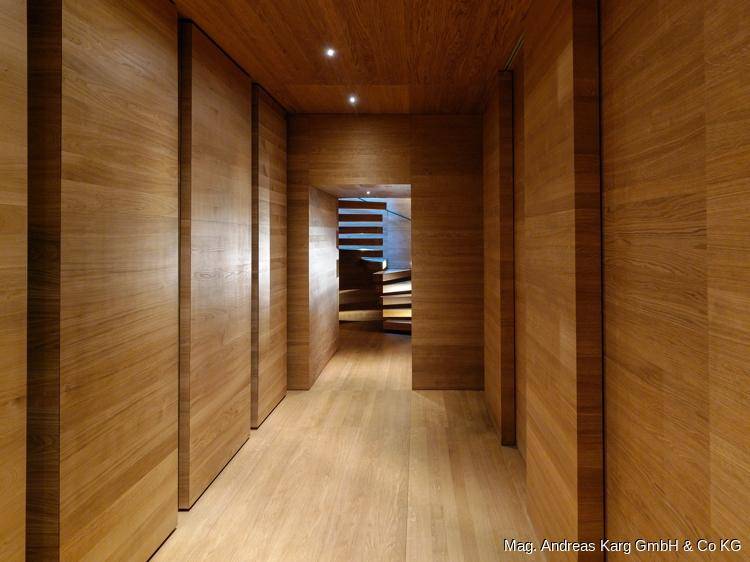 Holzverkleideter Flur mit integrierten Schränken und Blick auf eine weitere Treppe.