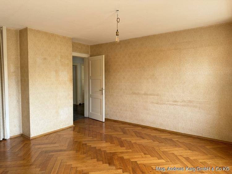 Geräumiges Zimmer mit Fischgrätparkett und heller Tapete, bereit zur individuellen Gestaltung.