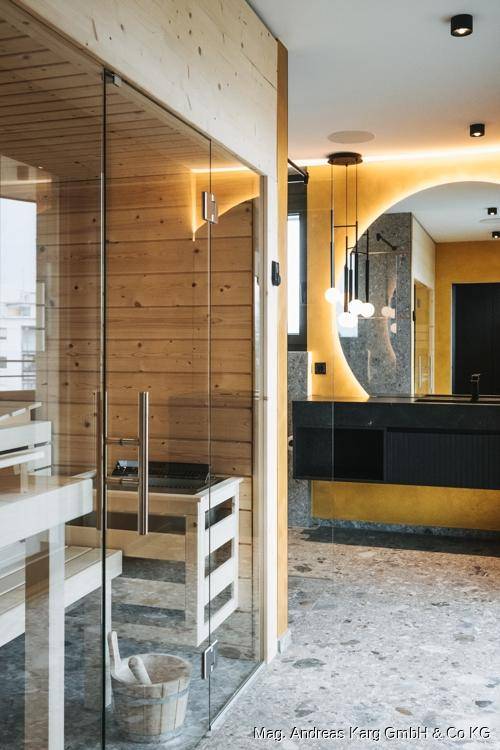 Wellnessbereich mit Sauna und modernem Badezimmer mit Doppelwaschbecken und stilvoller Beleuchtung.