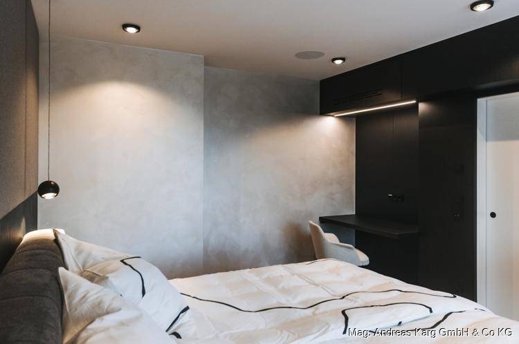 Schlafzimmer mit stilvollem Design, bequemen Bett, grauer Akzentwand und indirekter Beleuchtung.