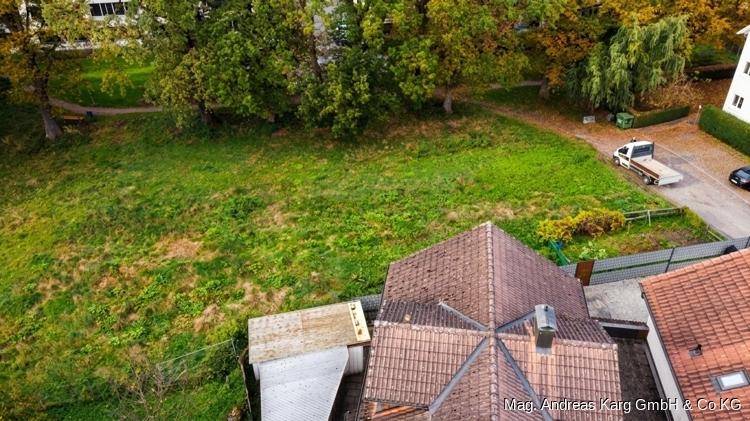 Luftaufnahme eines Gebäudes mit markantem Ziegeldach, umgeben von Bäumen und Grünflächen im Herbst.