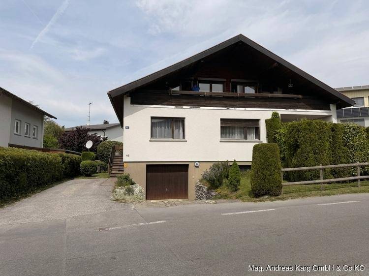 Ansicht des Einfamilienhauses von der Straße mit Garage und Balkon im Obergeschoss.