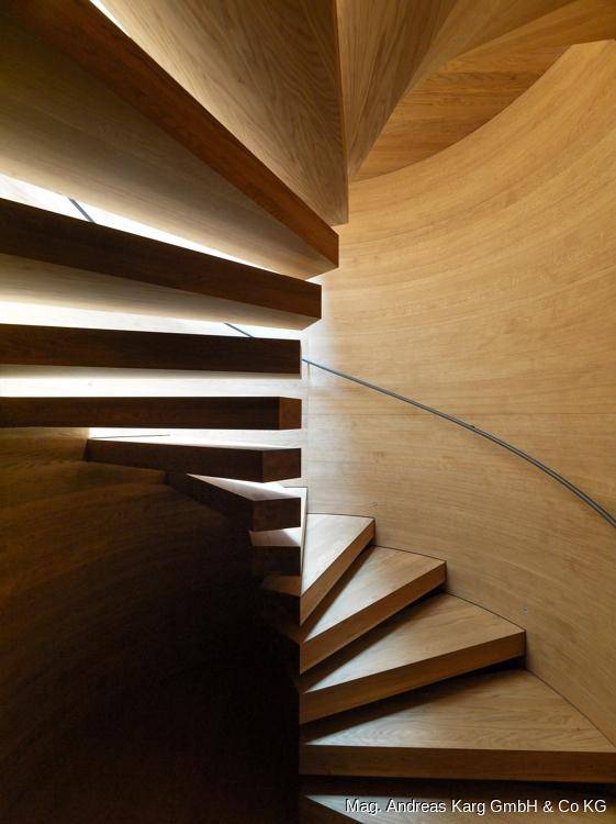Elegante Holzwendeltreppe mit indirekter Beleuchtung und minimalistischem Handlauf.