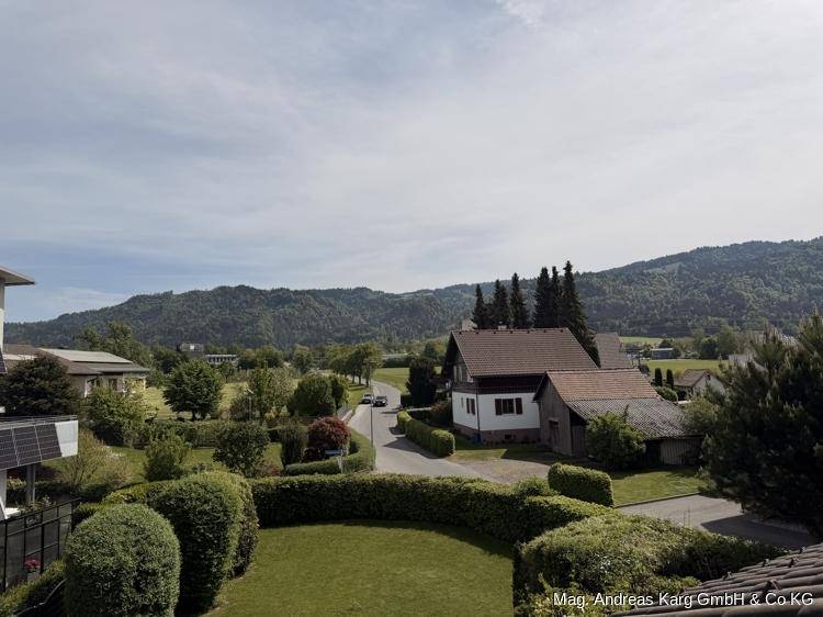 Weitläufiger Blick über die Nachbarschaft und grüne Hügel mit bewaldeten Bergen im Hintergrund.
