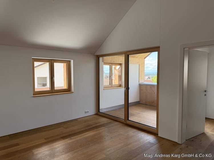 Geräumiges Zimmer mit Holzboden, großen Fenstern und direktem Zugang zu einem sonnigen Balkon mit Weitblick.