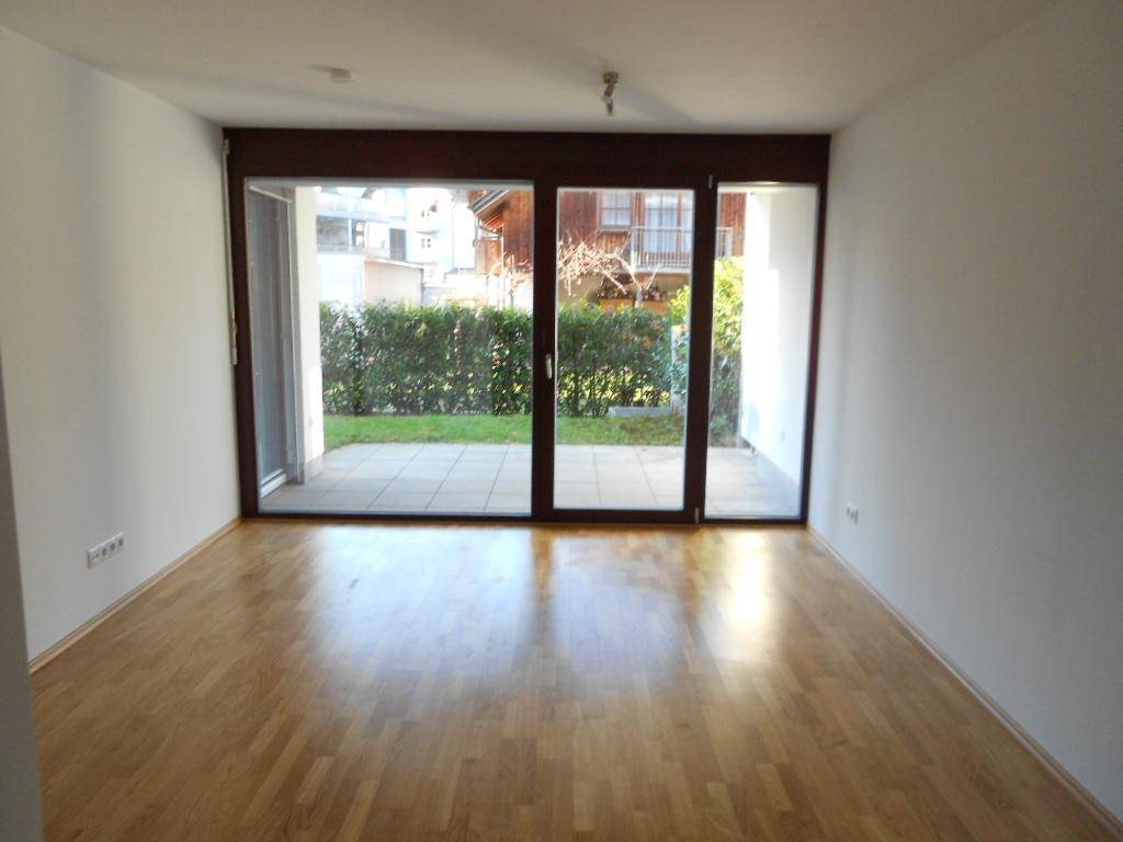Heller Wohnraum mit Parkettboden und großen Glasschiebetüren zum Gartenbereich.