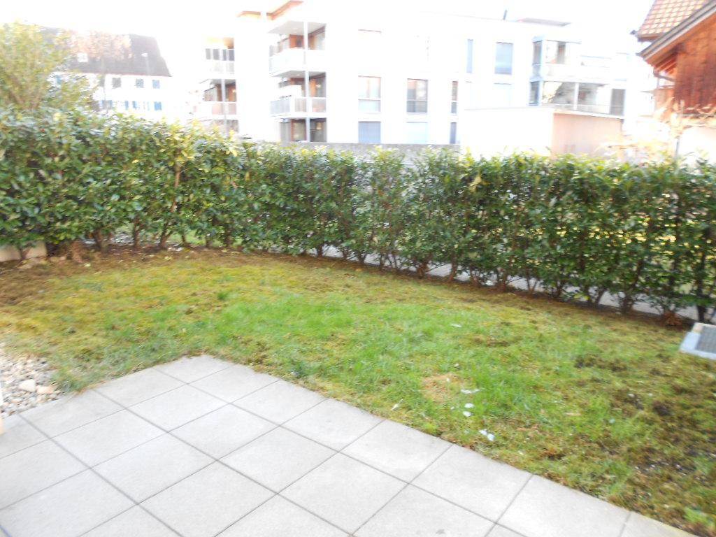 Kleiner privater Gartenbereich mit gefliester Terrasse und grüner Hecke.