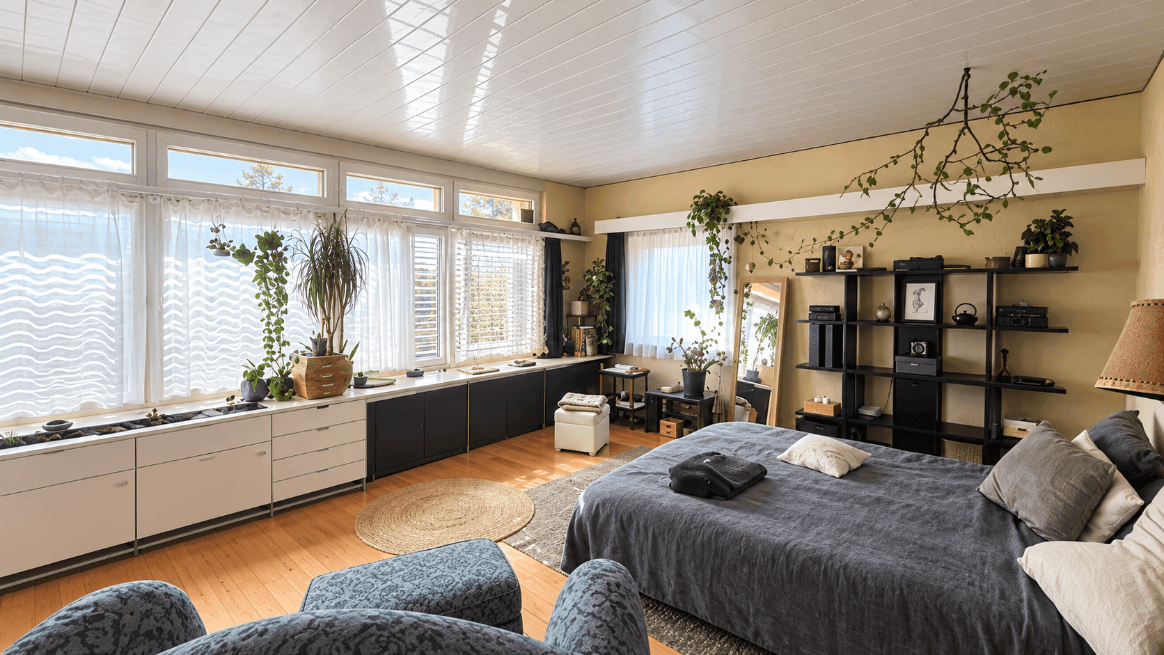 Helles Schlafzimmer mit vielen Pflanzen, einem großen Spiegel und praktischen Regalen.