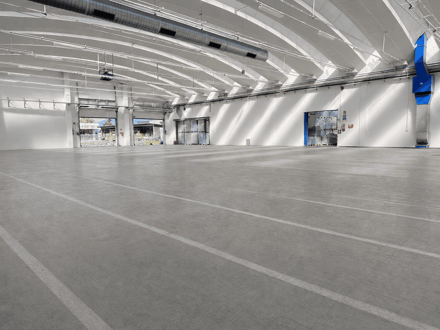 Geräumige Lagerhalle mit mehreren Rolltoren, Betonboden und natürlichem Lichteinfall durch Oberlichter.