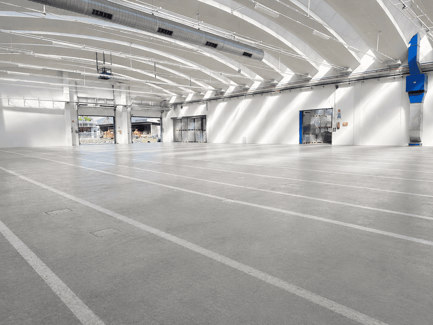 Geräumige Lagerhalle mit mehreren Rolltoren, Betonboden und natürlichem Lichteinfall durch Oberlichter.