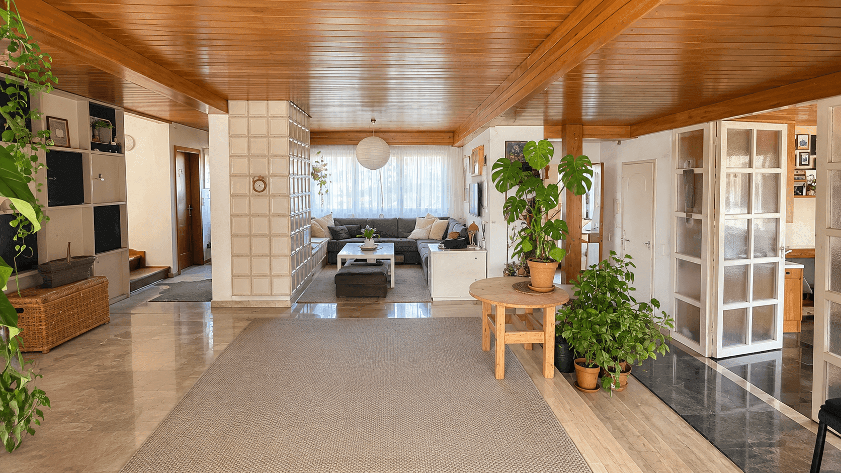 Geräumiger Flur mit Marmor- und Holzfußboden, Holzdecke und einer Glasbausteinwand.
