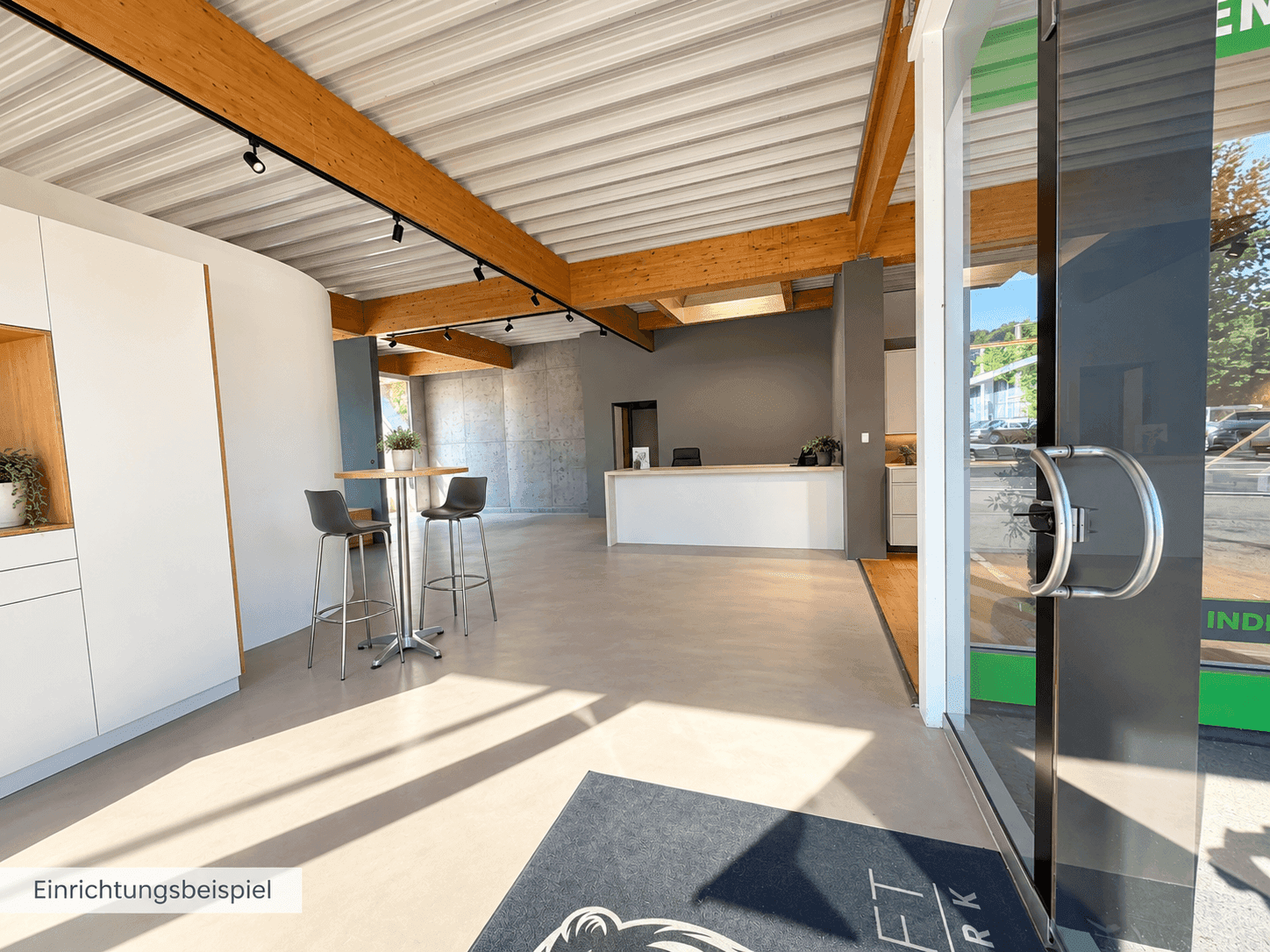 Heller Empfangsbereich mit hohen Decken, Holzbalken und großzügiger Glasfront.