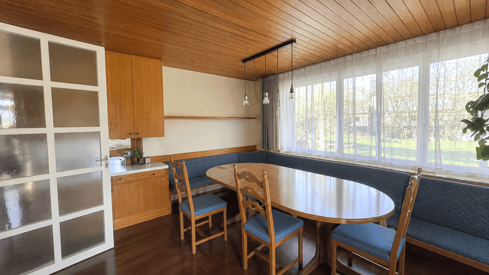 Gemütlicher Essbereich mit großem Holztisch, eingebauter Sitzbank und Holzdecke.