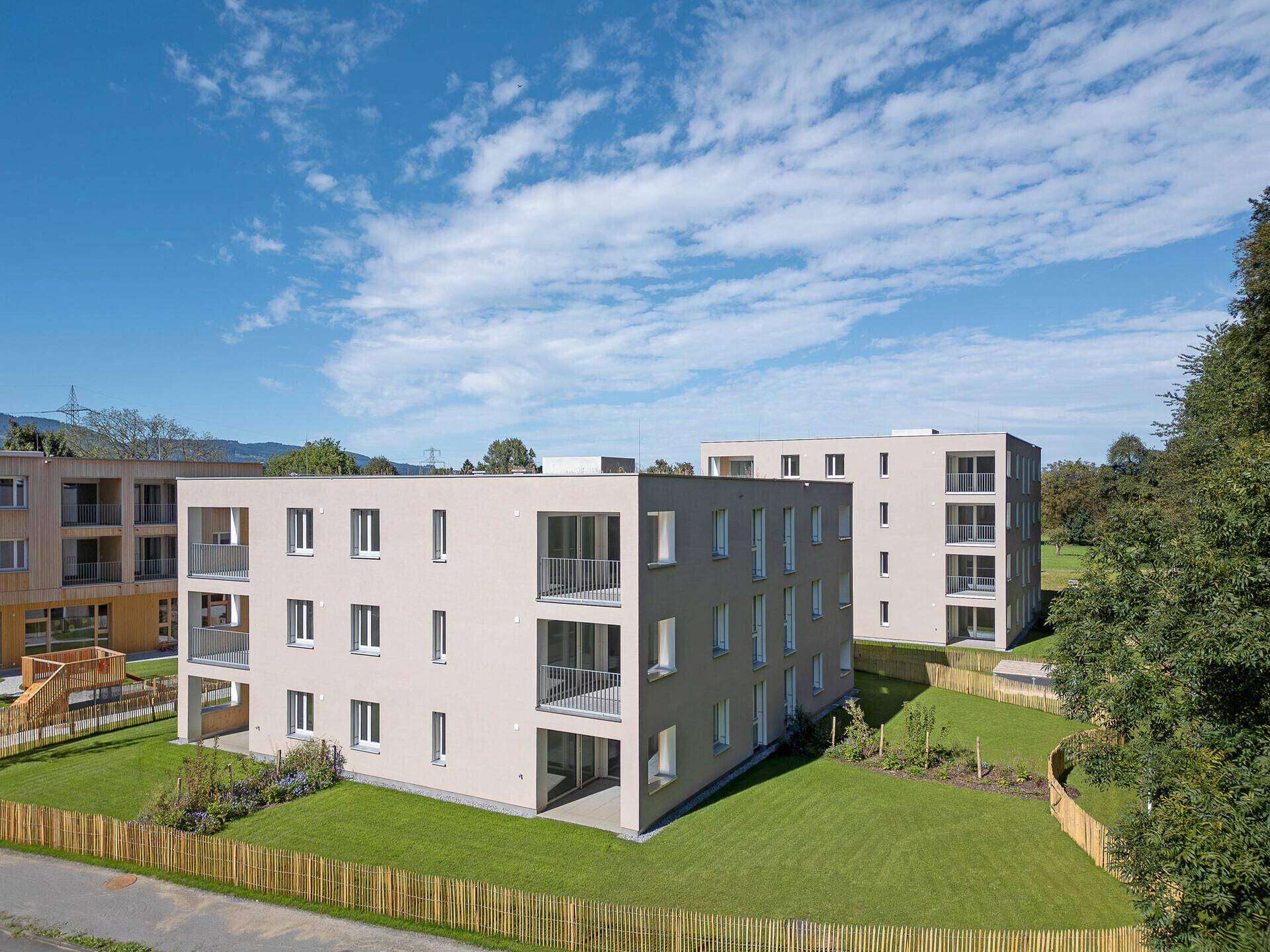 Neubauwohnungen mit Balkonen und gepflegten Grünflächen unter blauem Himmel.