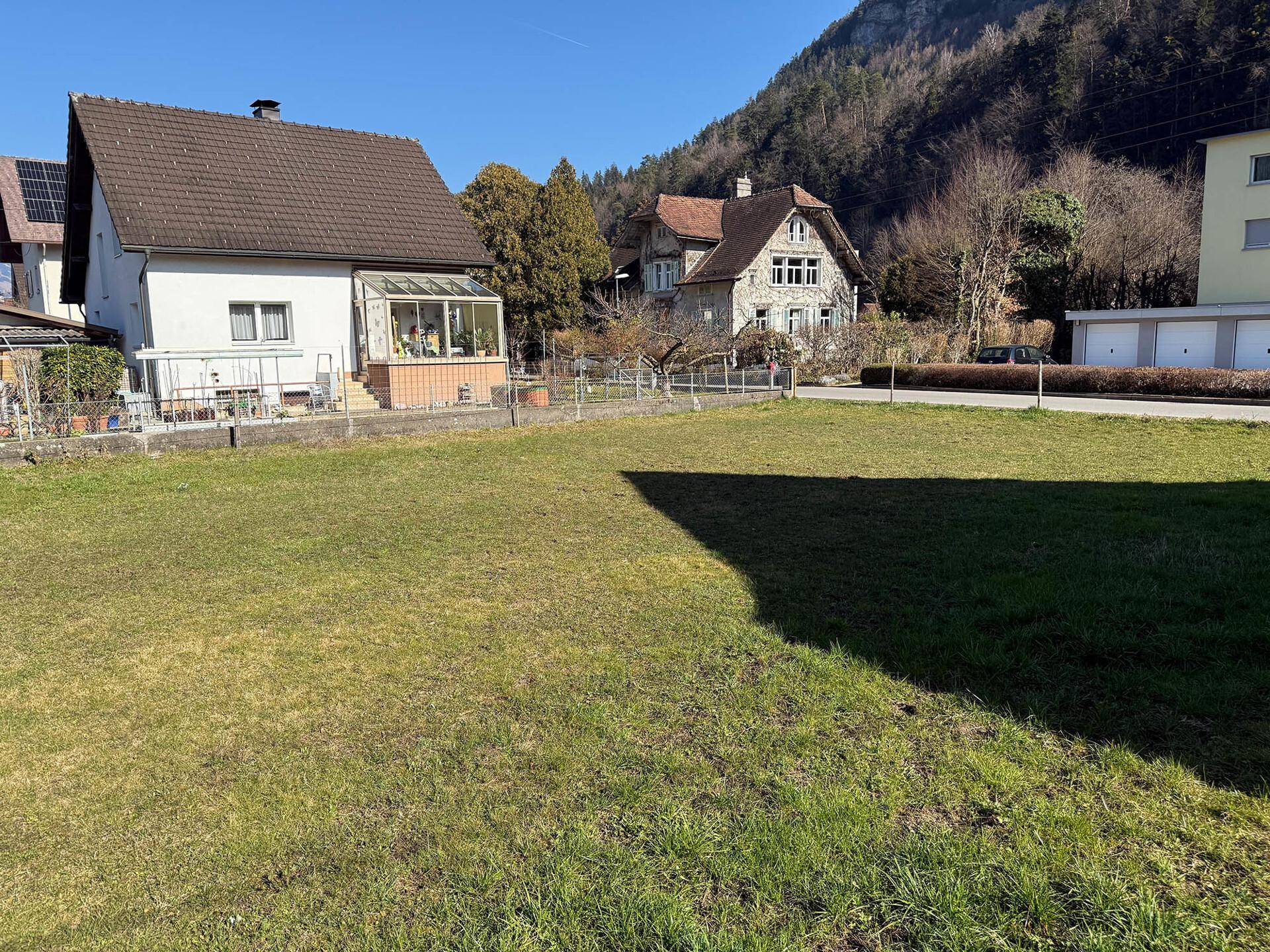 Weitläufiges Grundstück mit Blick auf die umliegende Berglandschaft und Wohnhäuser.