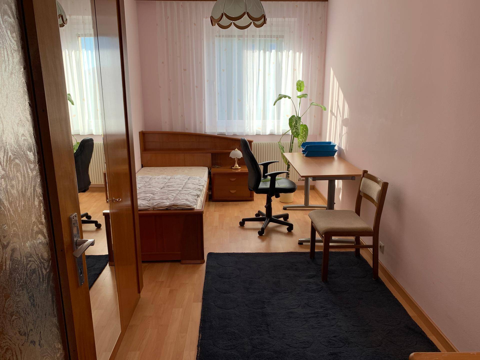 Gemütliches Schlafzimmer mit Einzelbett, Schreibtisch und großem Kleiderschrank.