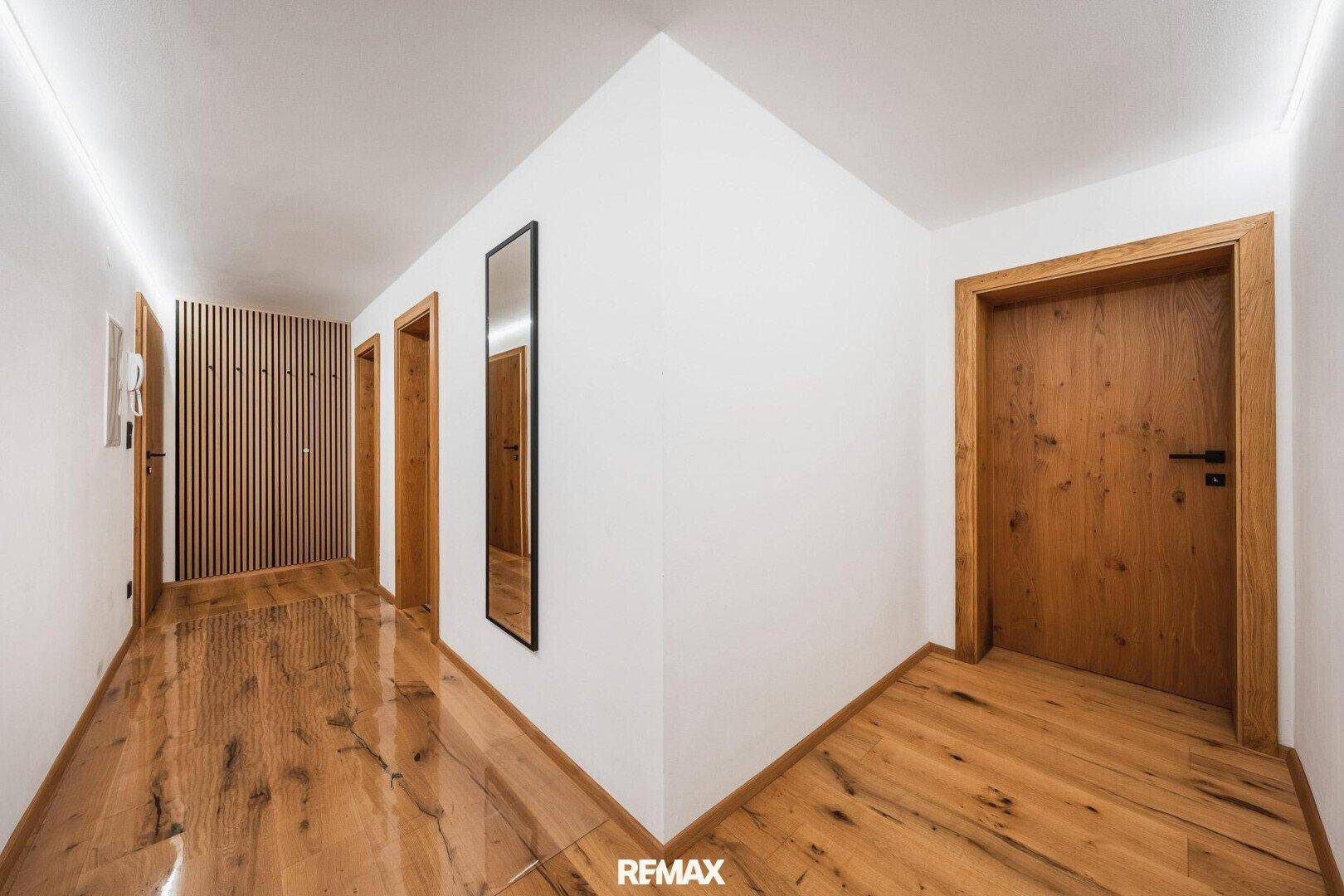 Moderner Flur mit Holzboden, Holztüren und dekorativer Holzlamellenwand.