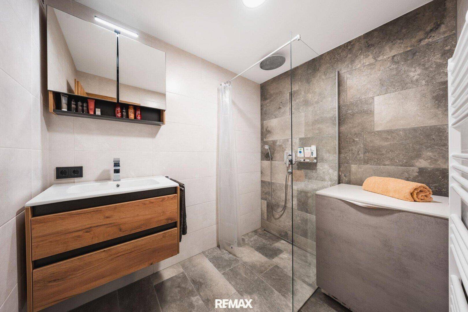 Modernes Badezimmer mit begehbarer Dusche, Holzwaschtisch und beheiztem Handtuchhalter.