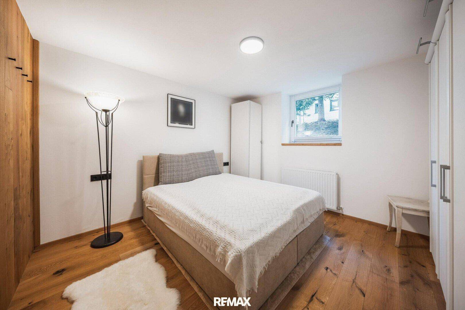 Komfortables Schlafzimmer mit Holzboden, großem Bett und Fenster.