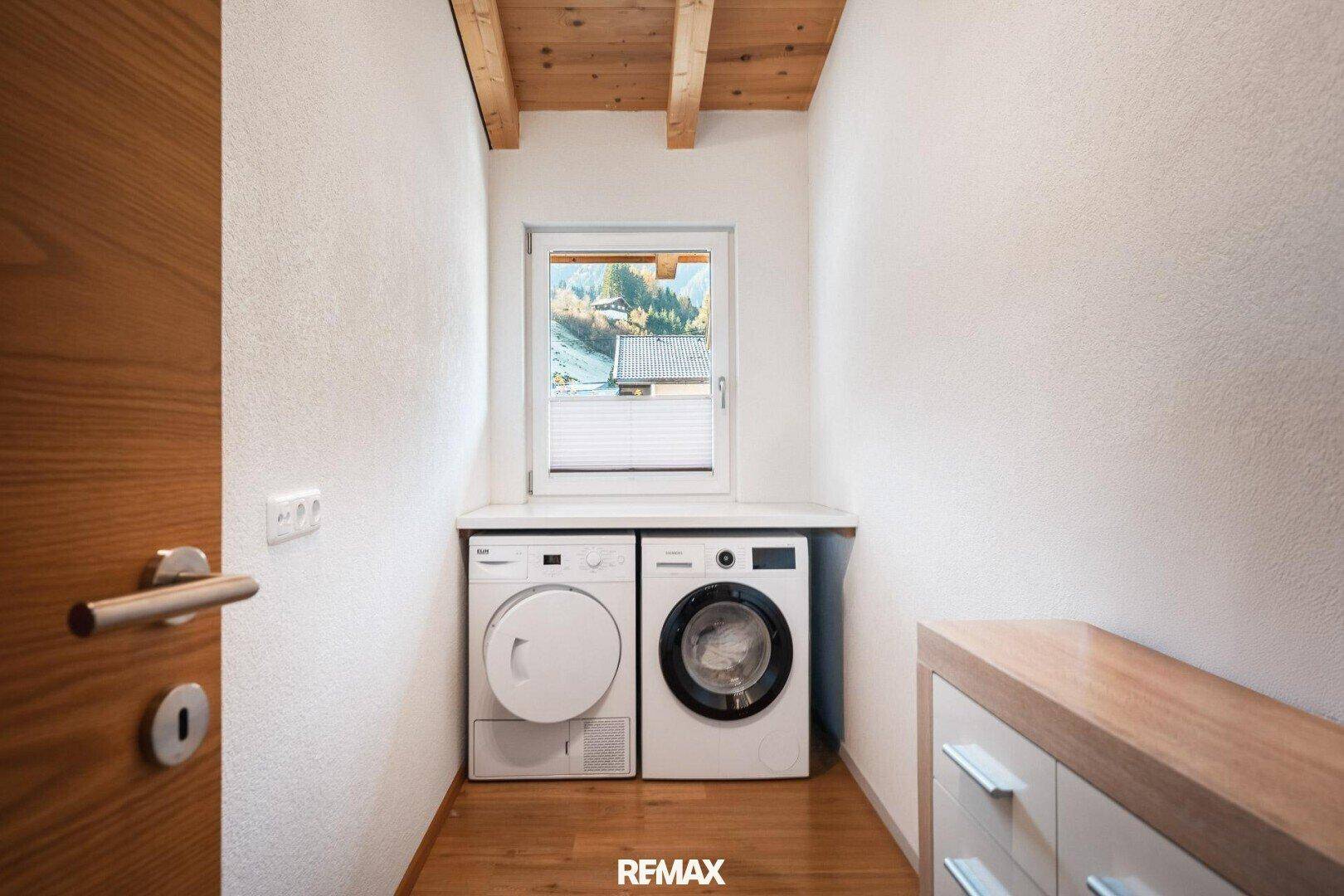 Praktischer Hauswirtschaftsraum mit Waschmaschine, Trockner und Fenster.
